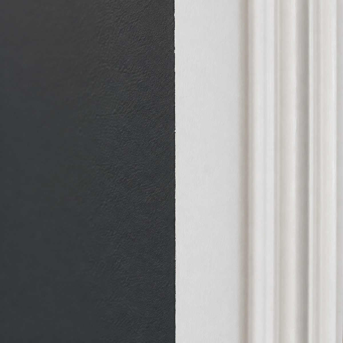 Extreme close-up of a crisp paint line where a charcoal wall meets bright white trim